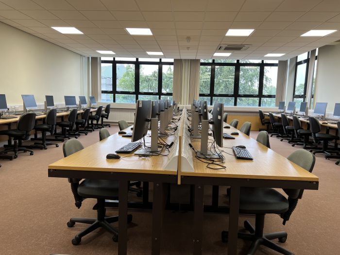 Flat floored teaching room with rows of PCs and monitors.