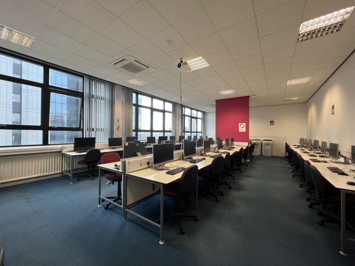 Flat floored teaching space with rows of PCs and monitors, and projector.