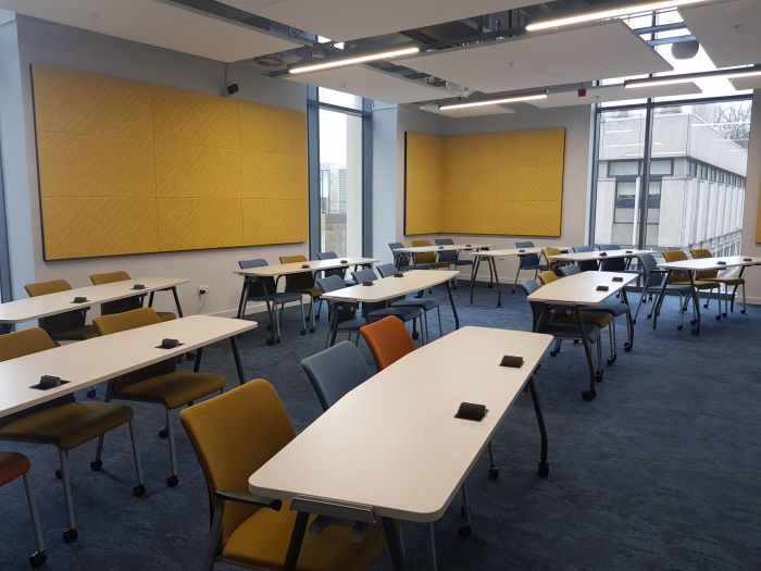Flat floored teaching room with rows of tables and chairs.