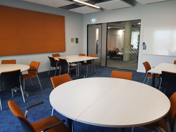 Flat floored teaching room with tables and chairs in groups.