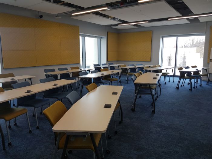 Flat floored teaching room with rows of tables and chairs.