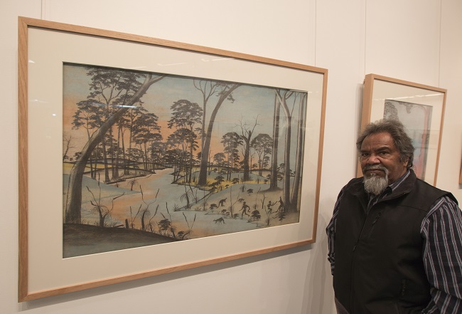 Goreng Noongar Elder Ezzard Flowers at the opening of the Koolark Korl Kadjin exhibition in Katanning, Western Australia in 2015, with artwork by Barry Loo, At Bay c1949. Photo by Brad Coleman, John Curtin Gallery
