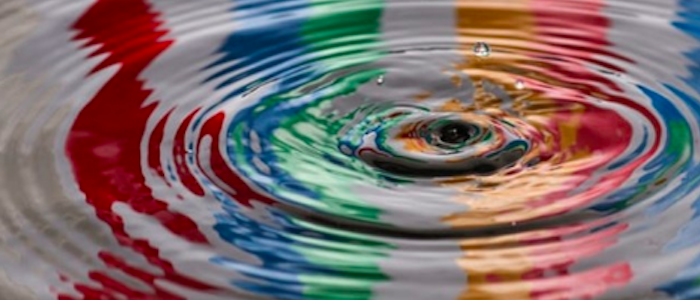 Ripples in a pool of water with coloured stripes reflected in it