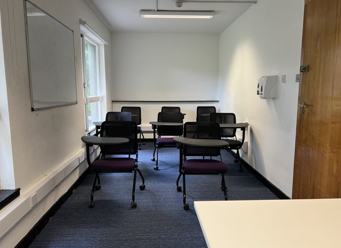 Flat floored teaching room with tablet chairs and whiteboard.