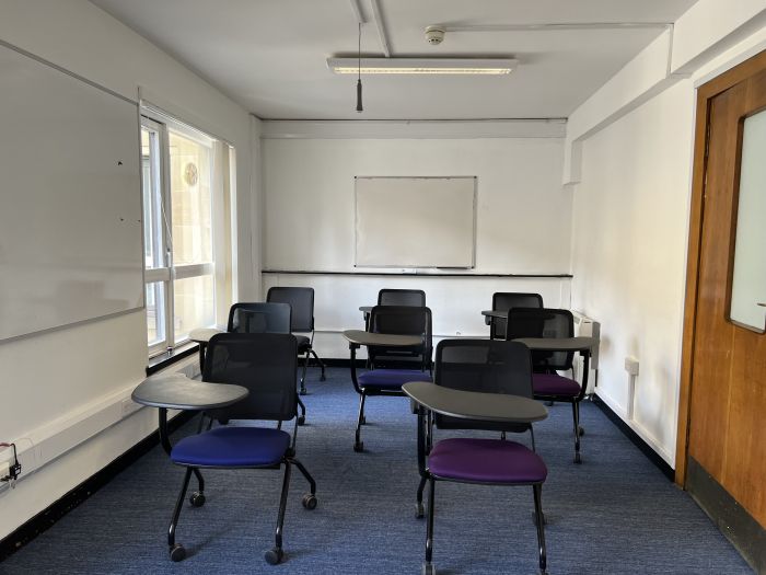 Flat floored teaching room with tablet chairs and whiteboards.