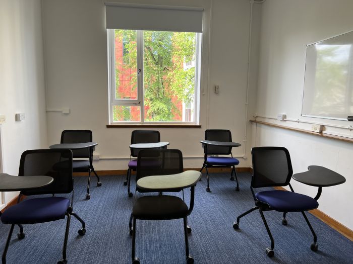 Flat floored teaching room with tablet chairs and whiteboard.