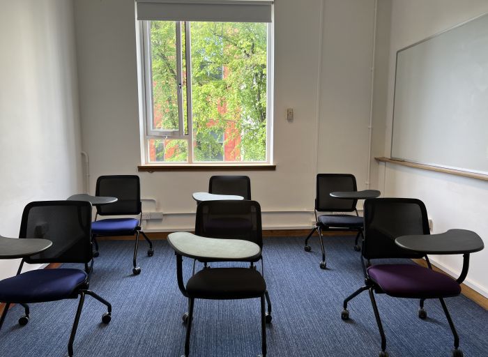 Flat floored teaching room with tablet chairs and whiteboard.