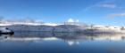 An image of snow-covered hills and a river under blue skies