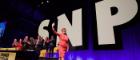 Nicola Sturgeon waving at a crowd at an SNP conference with panellists clapping behind her and a SNP logo behind her on stage Source: Terry Murden Publisher:Shutterstock Link: https://enterprise.shutterstock.com/catalog/licenses