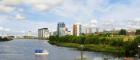 A series of flats on Glasgow's harbour with a small park in front next to a river with a small boat on the river. Source: Vetas | iStockphoto https://www.istockphoto.com/photo/passenger-ferry-sailing-from-govan-to-the-ferry-terminal-gm508125903-45512622 