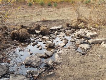 A small pool of water with large rocks surrounded by grass is the source of the Luanhe River