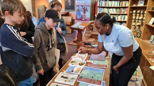 Photograph of a GSF in Action student with 3 people showing them insects and plant life surrounded by images of the insects. 