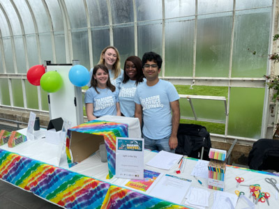 Photograph of four GSF in action students with colourful make your own glasses, and experiments to show light bending. 