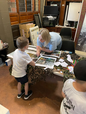 Photograph of a GSF in Action student with a child pointing at images of animal camouflage. 