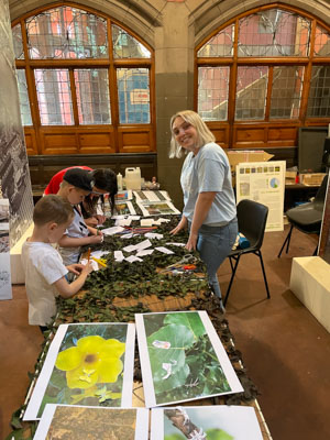 Photograph of a GSF in Action student smiling at the camera whilst assisting three children with the activity. 