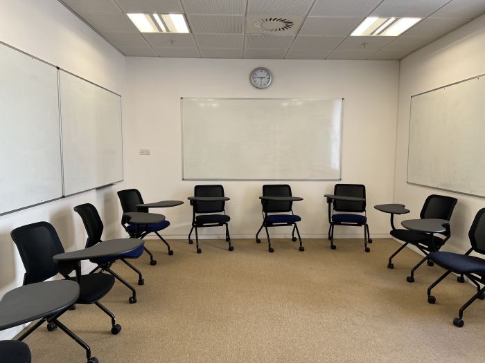 Flat floored teaching room with tablet chairs and whiteboards.