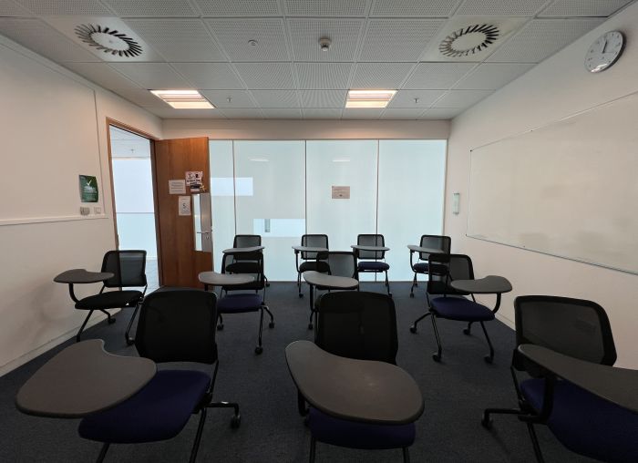 Flat floored teaching room with tablet chairs and whiteboard.