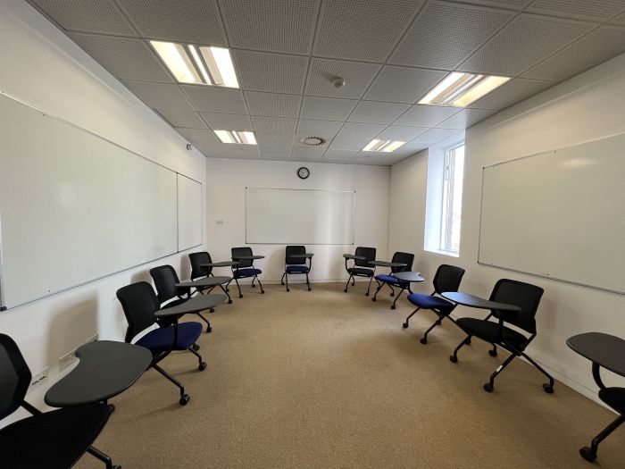 Flat floored teaching room with tablet chairs and whiteboards.