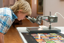 Photograph showing a child looking into a microscope. 