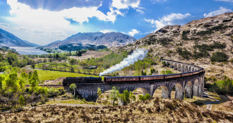 Glenfinnan Railway Viaduct in Scotland with the Jacobite steam train against sunset over lake