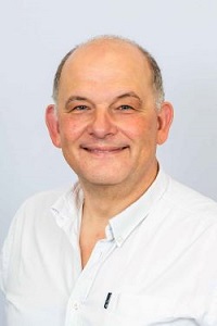Man wearing a white shirt smiling at the camera