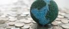 A small felt model of the Earth on top of coins. Image credit: utah778 | iStockphoto https://www.istockphoto.com/photo/global-finance-gm1127467564-297163314