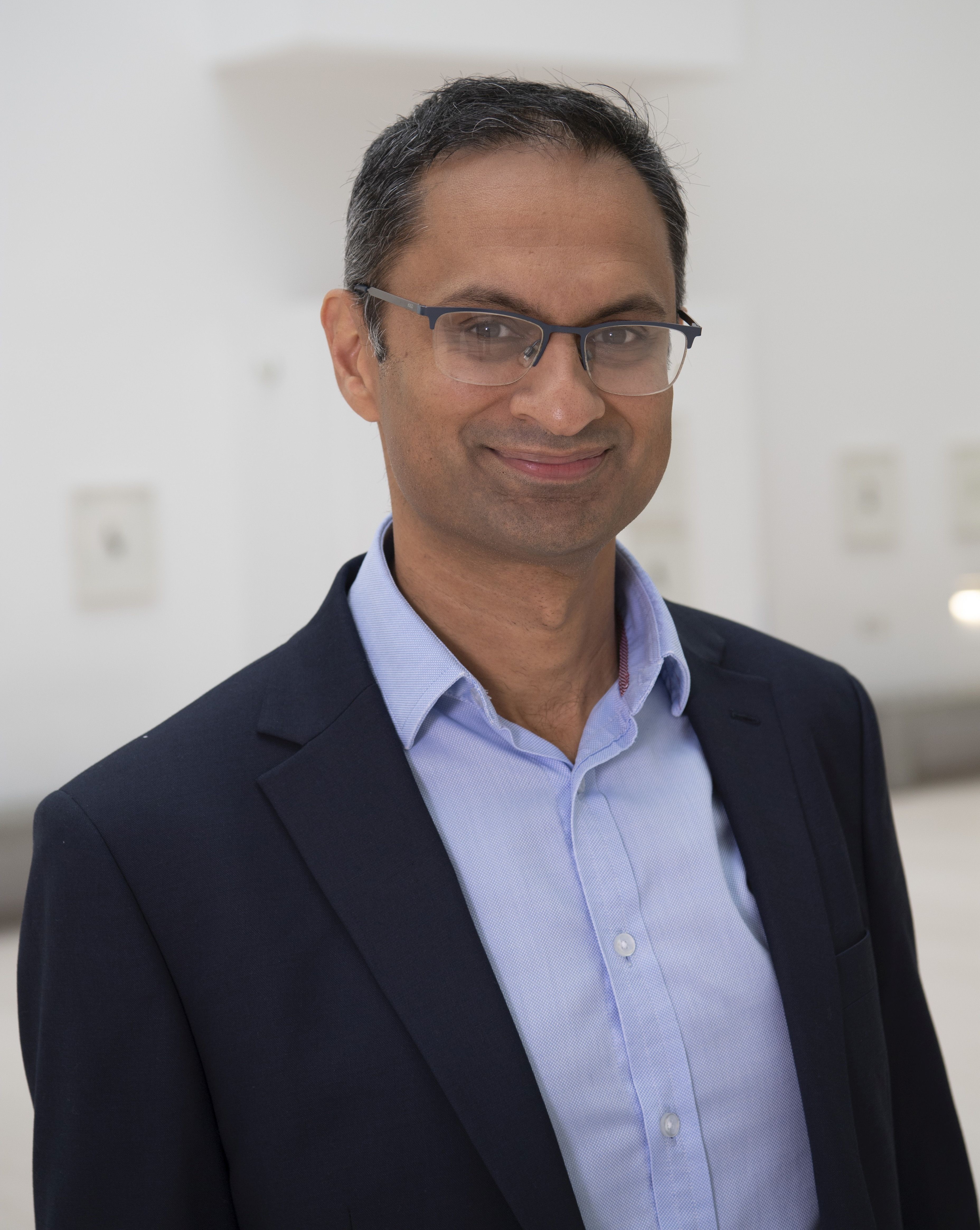 A head and shoulders shot of Professor Neil Basu in shirt and suit jacket