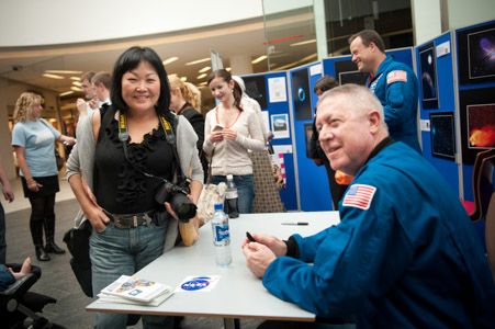Photograph showing a crowd of people at a table where NASA astronauts Mike Baker and Ron Garan are speaking. 