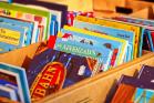 A stack of children's books in a wooden cart