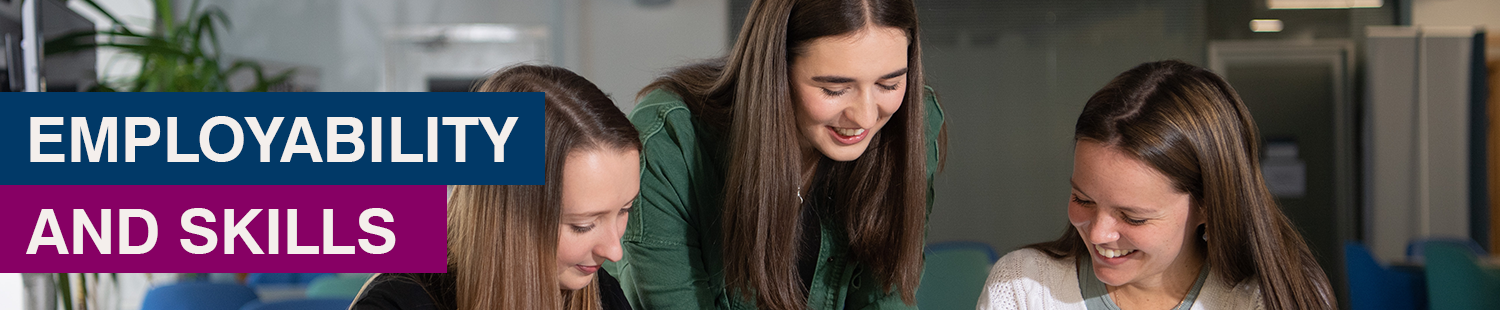 Students looking at something on a table and smiling