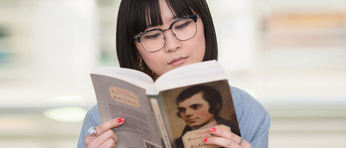 An image of a woman reading a book by Robert Burns 