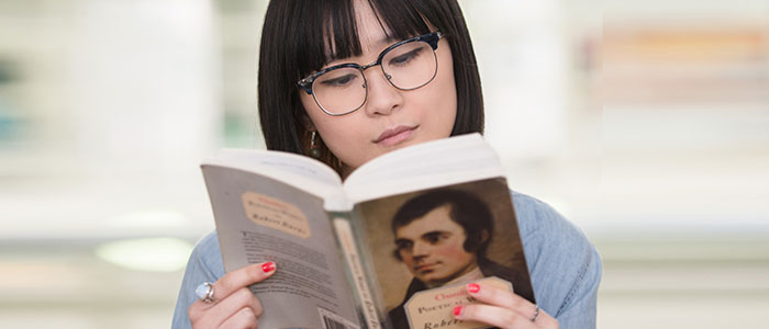 An image of a woman reading a book by Robert Burns