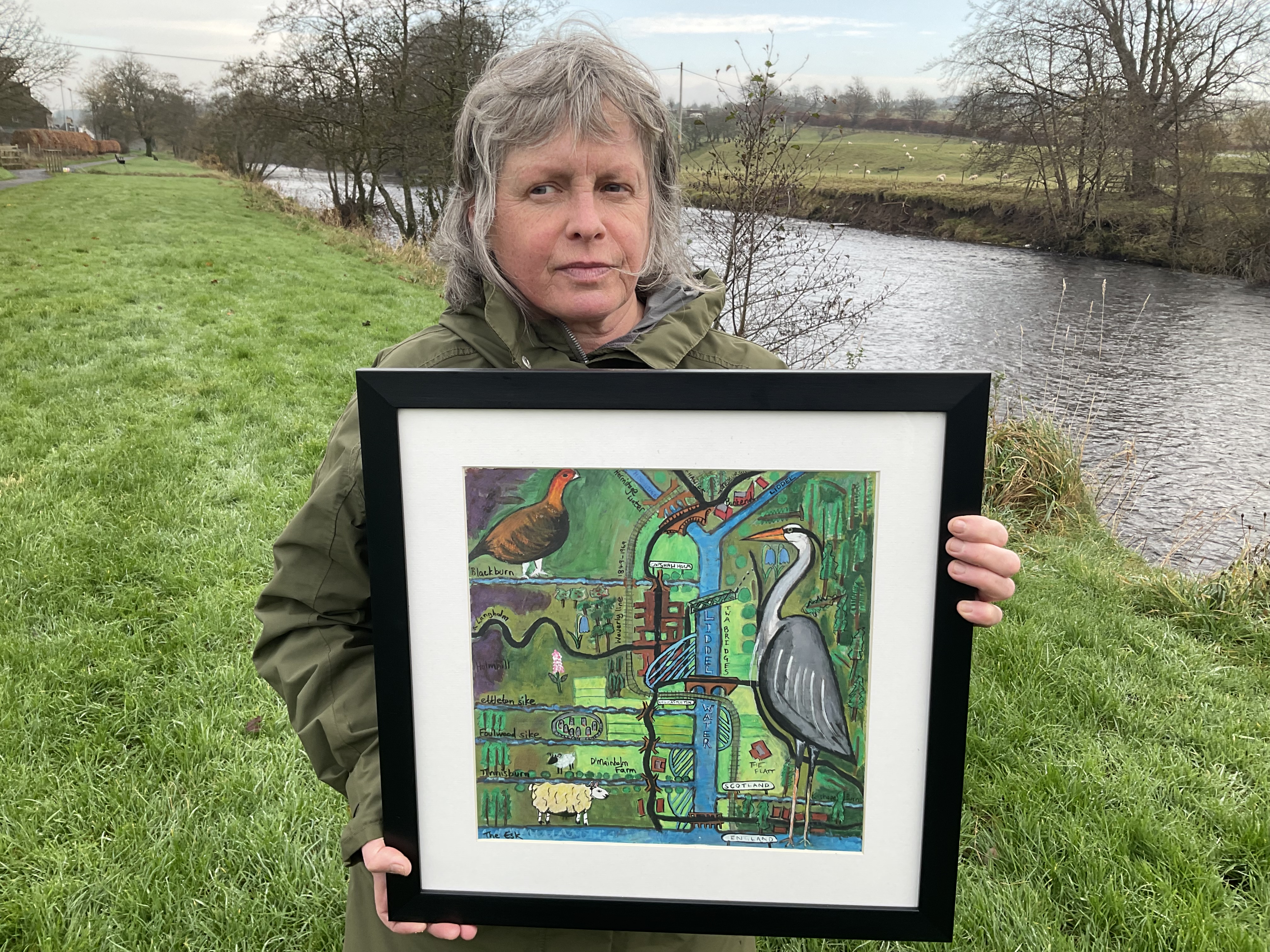 Woman holding artwork next to river