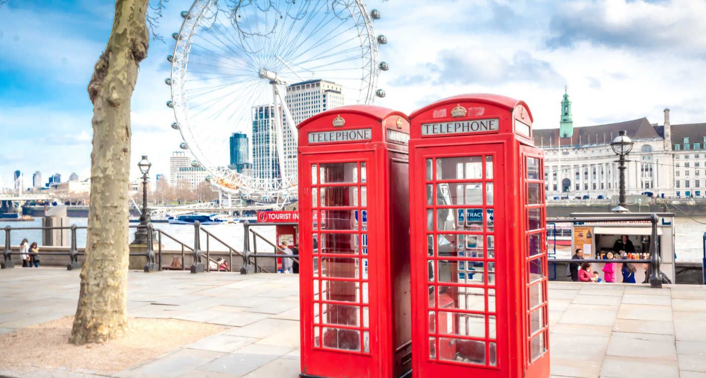 Two red phone boxes in the foreground with London Eye in the background [photo: Denian Mateus, Unsplash]