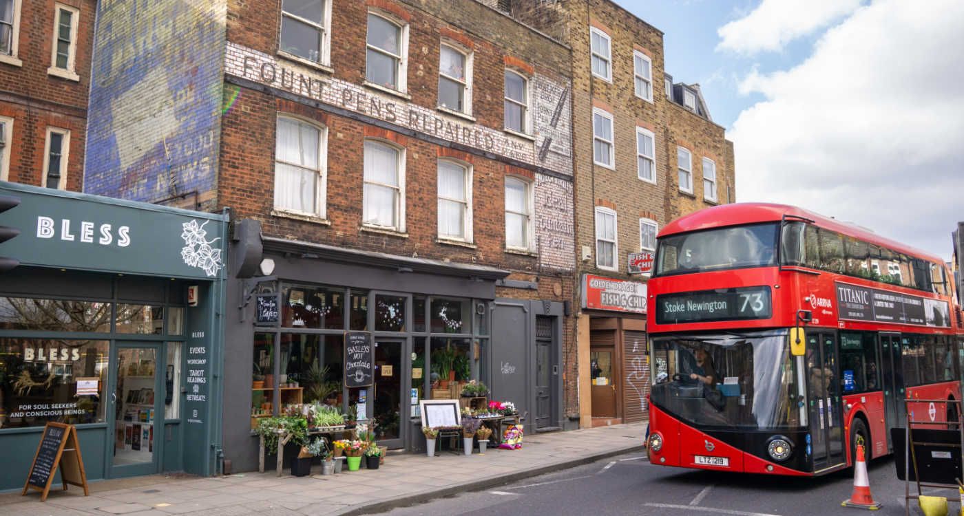 A row of shops in Stoke Newington Church Street with a red double decker driving past [photo: Shutterstock]