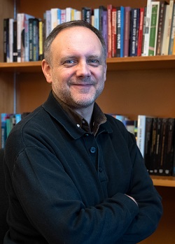 Head and shoulders image of a male wearing dark clothes