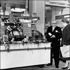 Photograph of salesman in the Grocery Department showing a customer a bottle of champagne, c1965.  
(GUAS Ref: HF 51/6/1/5/7 photo 2. Copyright reserved.)