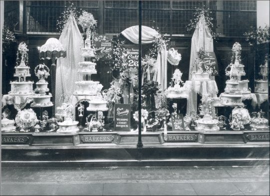 Photograph of a window display of wedding cakes and bridal bouquets. The price of wedding cakes then was 2/6d per lb, May 1929.  (GUAS Ref: HF 51/8/1/1/3 photo 15. Copyright reserved.)