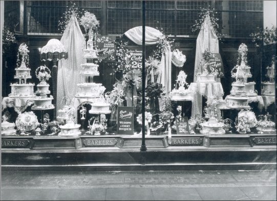 Photograph of a window display of wedding cakes and bridal bouquets. The price of wedding cakes then was 2/6d per lb, May 1929. (GUAS Ref: HF 51/8/1/1/3 photo 15. Copyright reserved.)