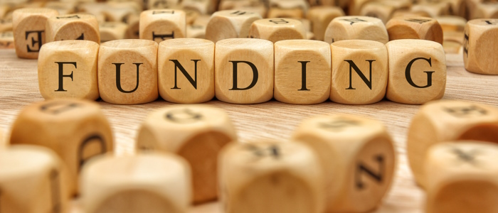 lettered die on a table with the word funding spelled out.