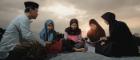 A woman and three girls wearing headscarves and a man sitting outside in a semi-circle and reading. Source: Pixabay Free to use under the Pixabay license No attribution required https://pixabay.com/photos/studying-teacher-students-sunset-5831644/