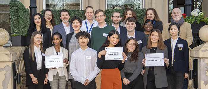 Students standing on a step for a group photo holding first, second and third place signs.