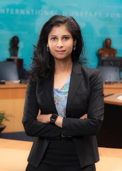 Photo of Gita Gopinath, standing with her arms folded, in a room with a large round conference table and busts on plinths. © International Monetary Fund. Source: https://www.imf.org/en/About/senior-officials/Bios/gita-gopinath