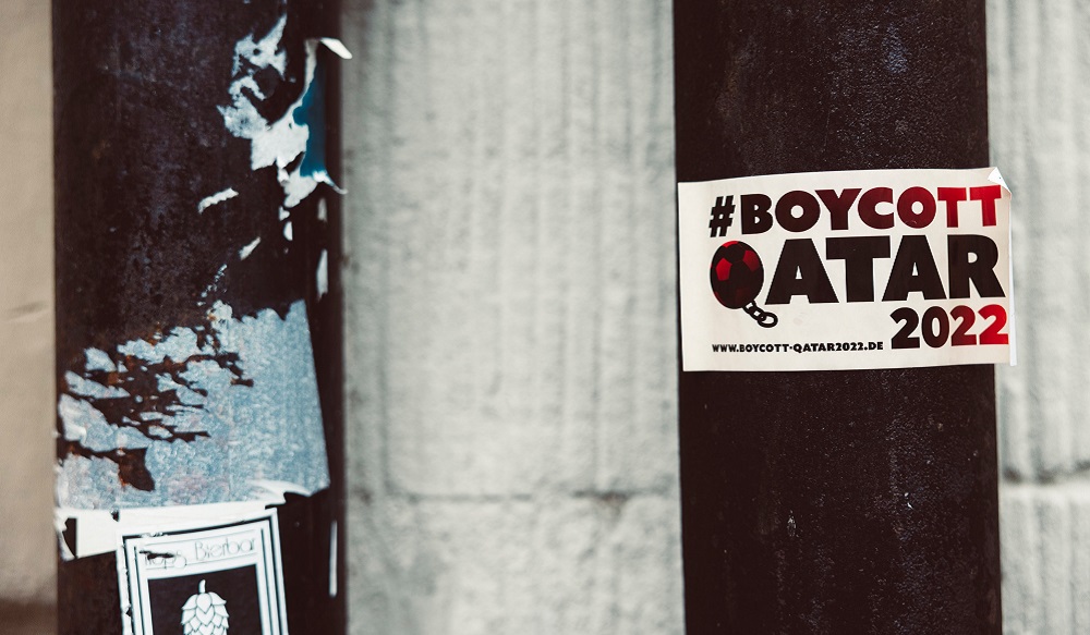 Sticker with the text '#BOYCOTT QATAR 2022. www.boycott-qatar.de' and an image of a football dragging a chain. Source: Markus Spiske on Unsplash https://unsplash.com/photos/0pKXTZSxqW4 Free to use under the Unsplash License