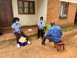 Three members of the COVSERO project sat outside a building in Malawi.