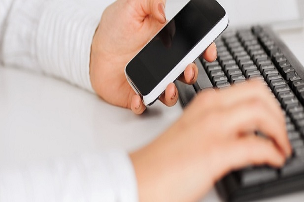 Phone in hand, typing on keyboard