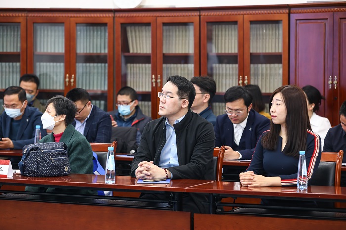A group of students at desks in a room with bookshelves behind them, paying attention as they listen to a speaker. Source:Peking University 
