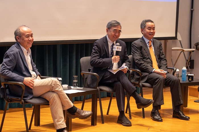 Three men sitting on chairs in front of an audience and laughing as they talk. Source: Hong Kong University 