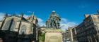 Adam Smith statue in Kirkcaldy from the front, with buildings in the background and blue sky