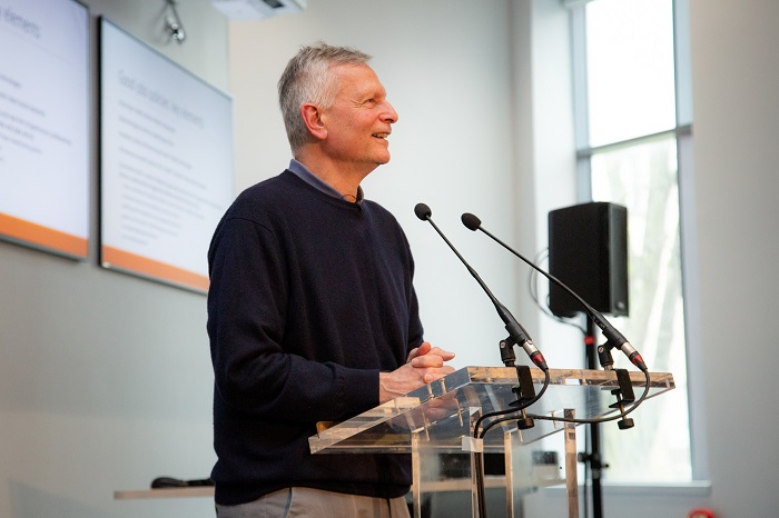 A man speaking at a podium with microphones with presentation slides behind him. Source: University of Glasgow